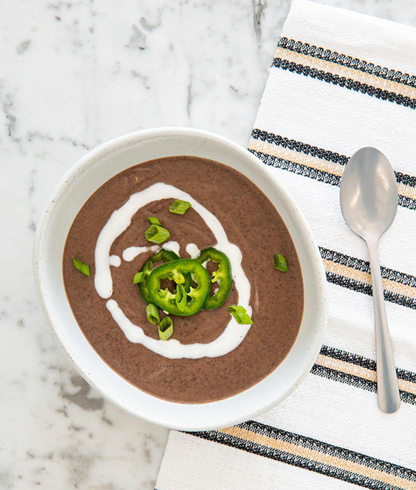 jalapeño recipes: bowl of black bean coconut soup topped with coconut cream swirl