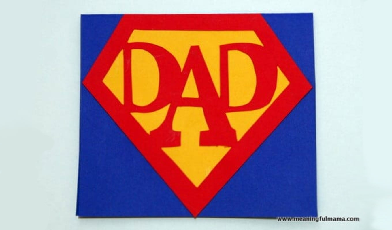 fathers-day-crafts: A blue father's day card featuring a Super Man motif using the words Dad in red letters in the red and yellow Super Man logo. The card is on a light blue background. There is a line of black text featuring the name of the website this craft comes from.
