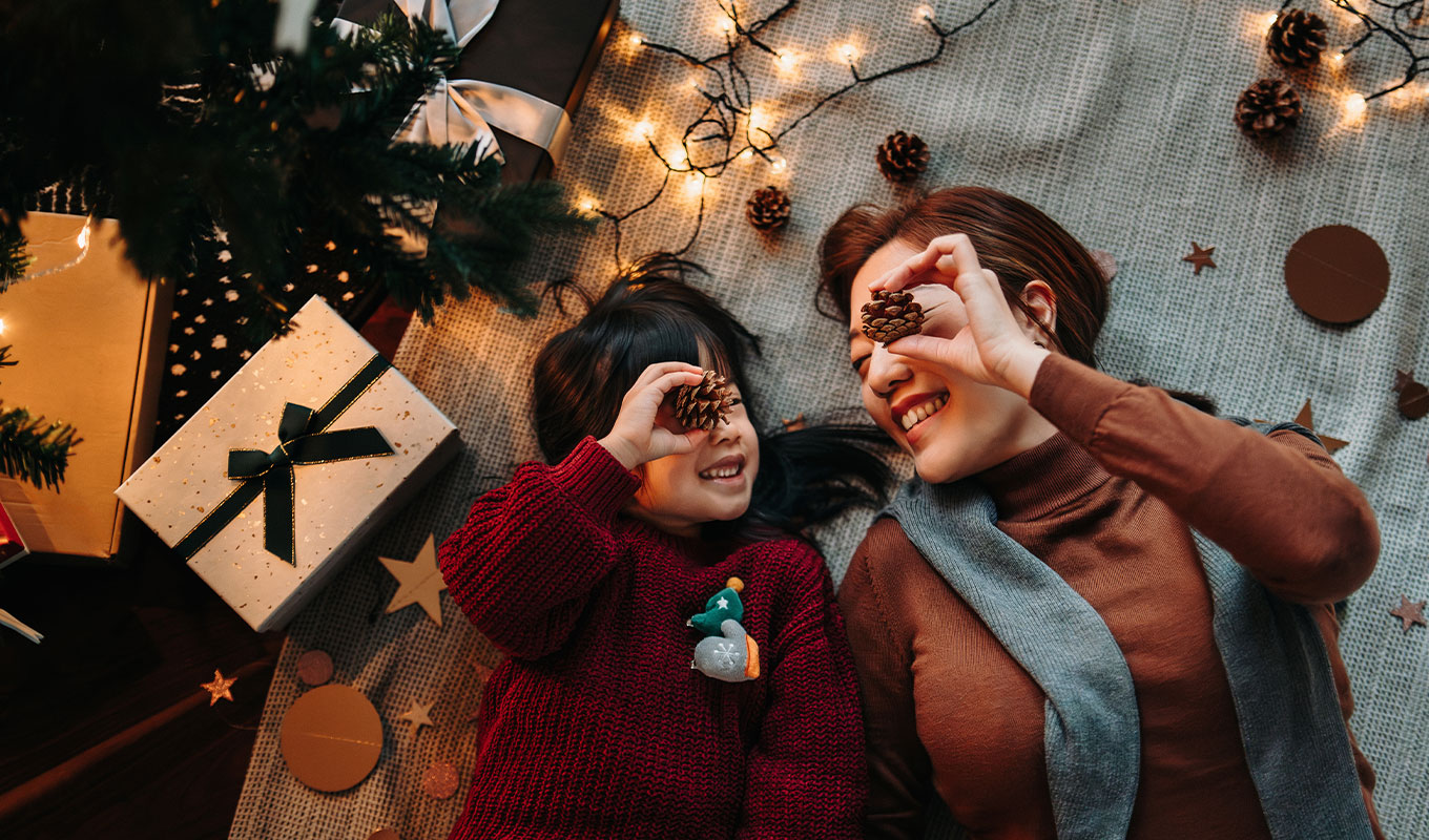 fun-things-to-do-on-christmas-day-2025: a mom and daughter laying underneath a christmas tree