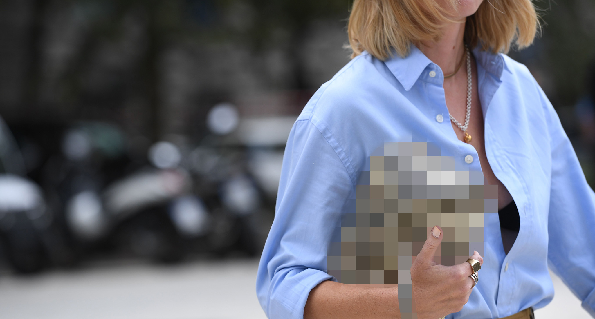 Woman in blue button up holding a blurred bag