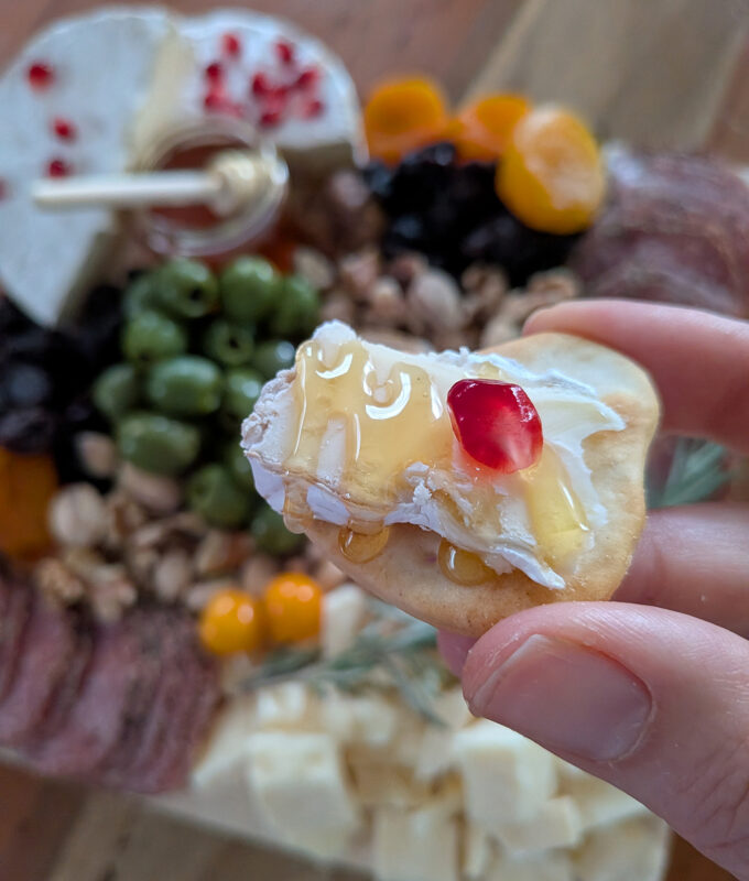 goldbelly charcuterie, holding cracker with brie and honey