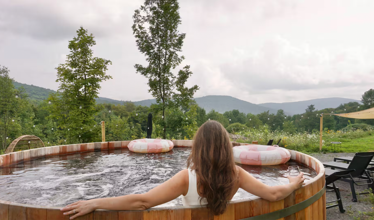 Airbnbs with pools in Upstate, New York: Woman lounging in wooden plunge pool outdoors