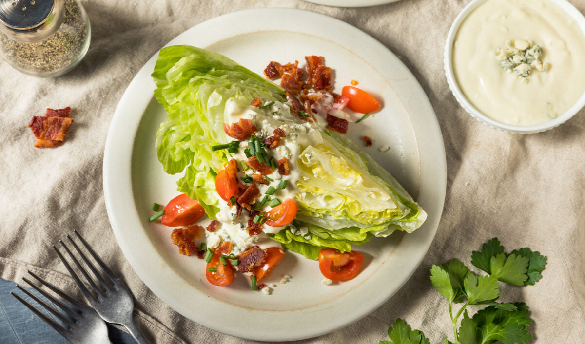 elitist work salads: an iceberg wedge salad topped with dressing, tomatoes and bacon