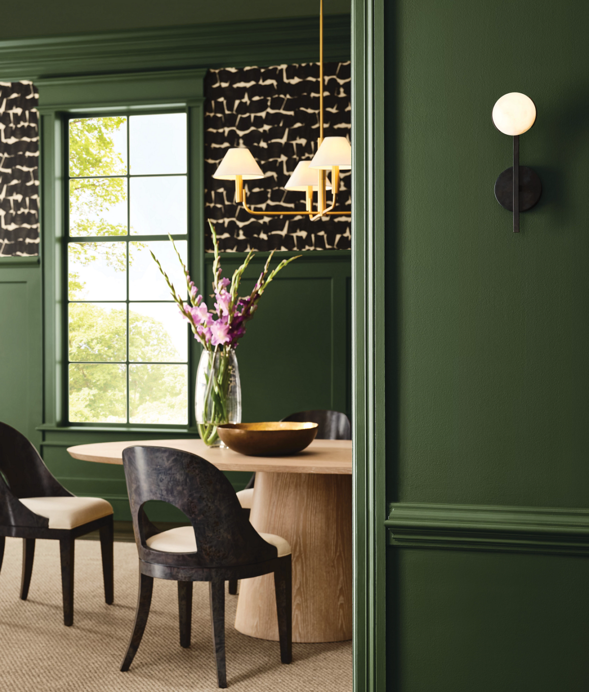 green dining room with black chairs and black and white script art on walls