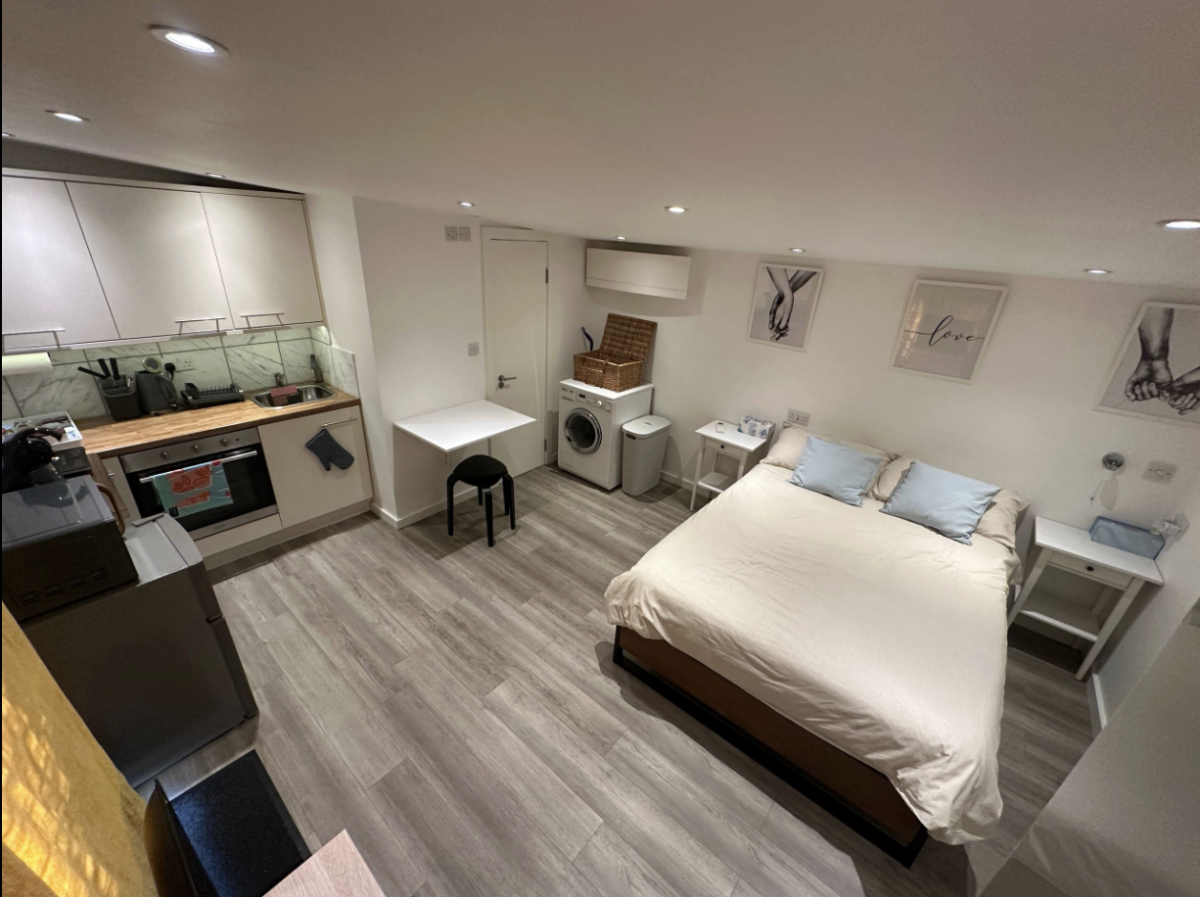 small apartment with bed with washing machine in room